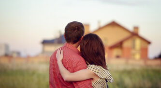 Young Couple embracing while looking at a house