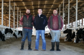 Banker and business owners standing proudly on dairy farm
